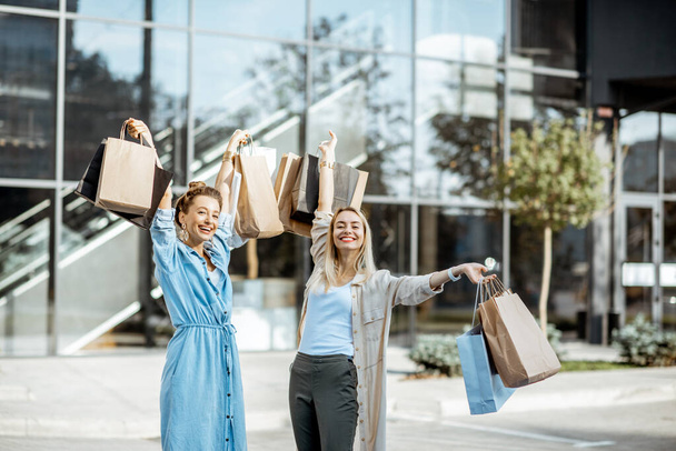 Женщины с сумками возле торгового центра на открытом воздухе
 - Фото, изображение