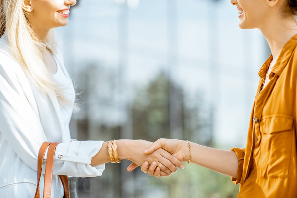 Businesswomen shaking hands outdoors - Фото, изображение