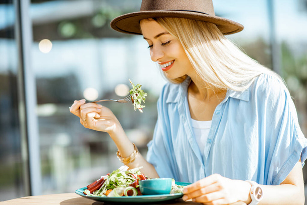 Mujer comiendo ensalada en una terraza cafetería
 - Foto, Imagen