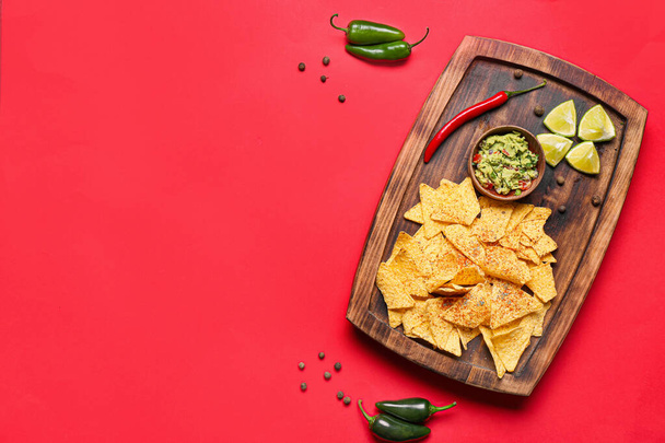 Tablero con sabrosos nachos y salsa de guacamole sobre fondo de color
 - Foto, imagen