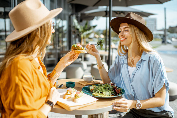Подружки їдять здорову їжу на терасі
 - Фото, зображення