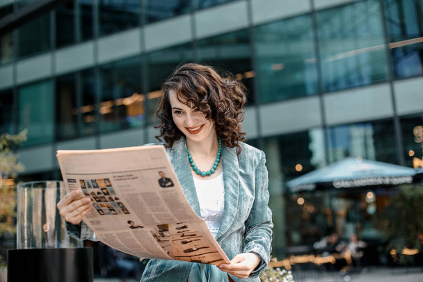 νεαρή γυναίκα διαβάζει μια εφημερίδα και ένα βιβλίο χαμογελώντας. Βαρσοβία, Πολωνία - Φωτογραφία, εικόνα