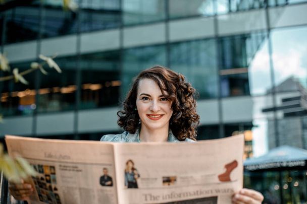 νεαρή γυναίκα διαβάζει μια εφημερίδα και ένα βιβλίο χαμογελώντας. Βαρσοβία, Πολωνία - Φωτογραφία, εικόνα