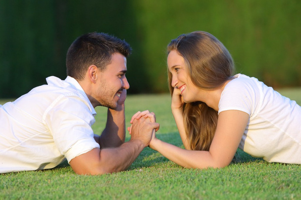 Couple flirting and looking each other lying on the grass - Foto, Imagem