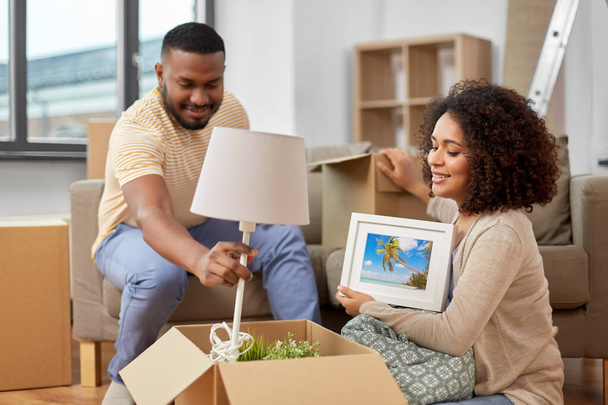 happy couple packing boxes and moving to new home - Foto, Bild