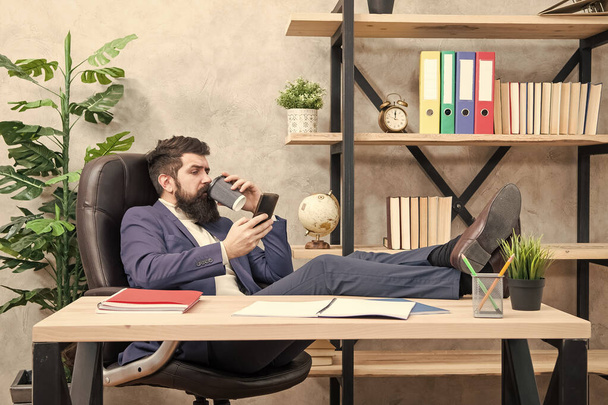 Coffee is pledge of successful negotiations. Caffeine addicted. Mobile call. Start day with coffee. Coffee relaxing break. Boss enjoying energy drink. Man bearded businessman hold cup and smartphone - Zdjęcie, obraz