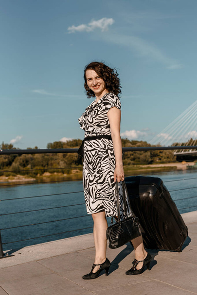 Young woman travels. Stylish girl by the river. The Vistula. Lady with a suitcase. Greeting. Vacation. Warsaw - Fotografie, Obrázek
