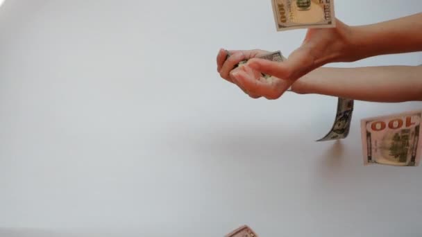 Womans hands catch two 100 US Dollar banknotes falling in slow motion against white background. - Footage, Video