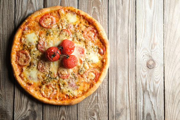 Traditional italian pizza with tomatoes, cheese, ham, mushrooms and arugula on a light rustic background top view copy space. - Photo, Image