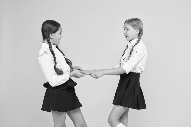 Schoolgirls fight for book. Protect property. Greedy friends. Greedy competitors. Jealous friend. Greedy kids concept. Sisters relations issues. Share book with friend. Classmates rivalry problem - Valokuva, kuva