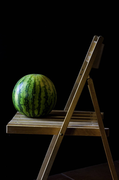 Wassermelone auf Holzstuhl und dunklem Hintergrund. rustikale Food-Fotografie - Foto, Bild