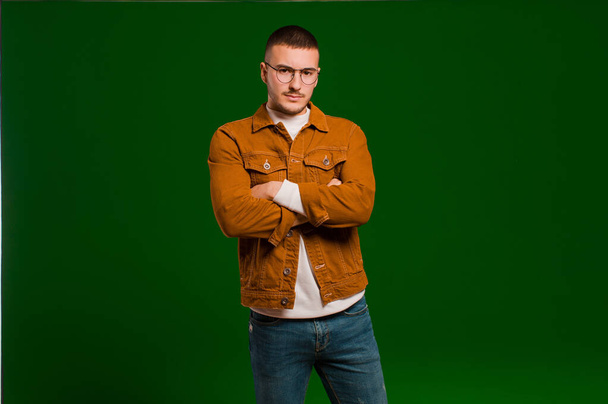 young handsome man feeling displeased and disappointed, looking serious, annoyed and angry with crossed arms against flat background - Foto, imagen