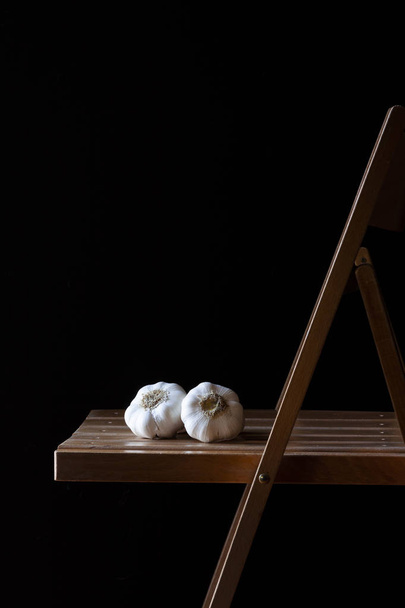WHITE GARLIC ON WOODEN CHAIR AND DARK BACKGROUND. RUSTIC FOOD PHOTOGRAPHY - Photo, Image