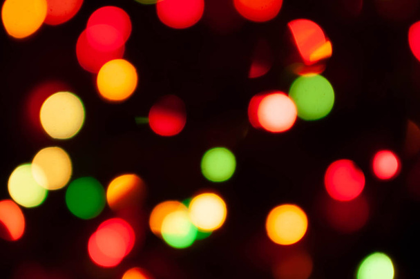 unfocused colorful christmas lights on dark background with bokeh effect and copy space - Valokuva, kuva