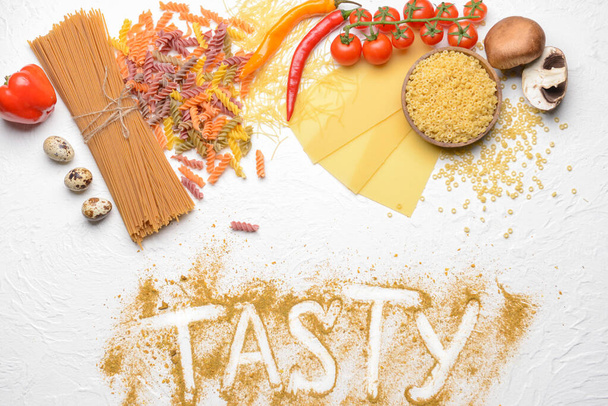 Composition with different uncooked pasta and products on white background - Photo, Image