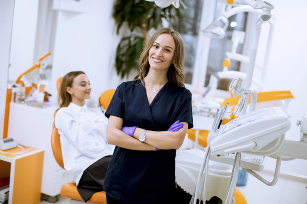 Atractiva joven dentista doctora de pie en su consultorio, mirando a la cámara
 - Foto, Imagen