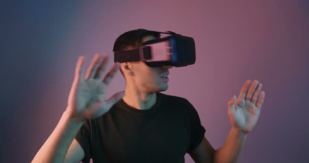 Portrait of male using VR Glassess in multicolor neon light. Young man in virtual reality helmet in futuristic neon lights. - Filmati, video