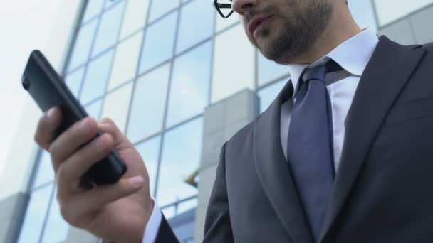 Angry businessman texting from smartphone outdoors nervous after reading message - Záběry, video
