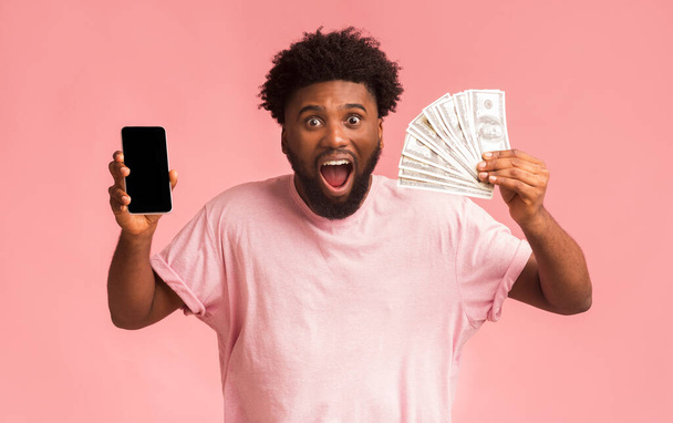 Verbazingwekkende man met smartphone en tonen een heleboel geld - Foto, afbeelding