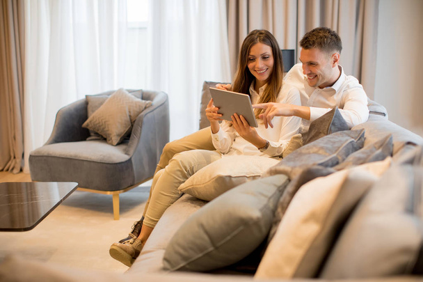 Krásný mladý pár s digitálním tabletem v pokoji moderního bytu - Fotografie, Obrázek
