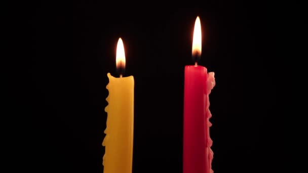 δύο αναμμένα κεριά κόκκινα και κίτρινα σε μαύρο φόντο - Πλάνα, βίντεο