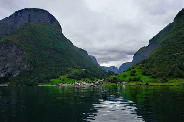 Kutsal Kase, Sognefjord ya da Sognefjorden 'dan resmedilmiştir. Mavi gökyüzü ve berrak sulardaki yansıma ile oluşturulmuş. Flam' deki bir nehirde ahşap bir rıhtıma sahip. - Fotoğraf, Görsel