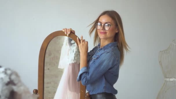 Gyönyörű varrónő szőke varró stúdió vizsgálja a ruha egy próbababa - Felvétel, videó