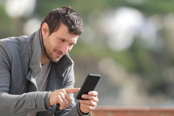 Homem sério verificando aplicativo de telefone móvel no inverno
 - Foto, Imagem