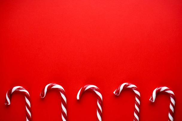Świąteczna kompozycja. Świąteczne cukierki na czerwonym tle. Tradycyjne świąteczne słodycze. Płaskowyż, miejsce na tekst. - Zdjęcie, obraz