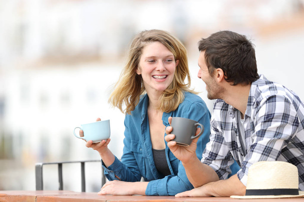Happy adult couple talking and drinking coffee in a balcony - Zdjęcie, obraz