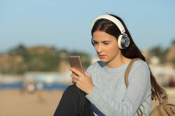 Serious girl listening to music checking smart phone - Zdjęcie, obraz