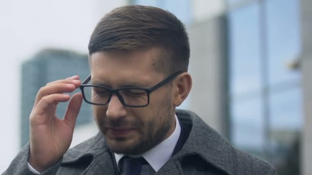 Young man taking off glasses and rubbing temples, suffering high blood pressure - Materiał filmowy, wideo