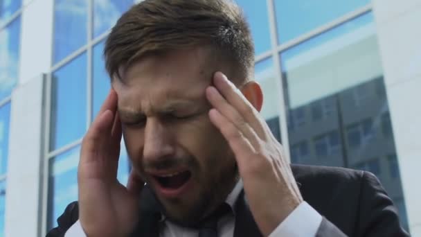 Tired businessman touching head in street, having bad headache, burnout at work - Materiał filmowy, wideo