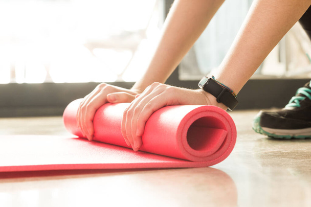 Foto stock de uma jovem mulher rolando o tapete depois de se exercitar em casa na sala de estar
 - Foto, Imagem