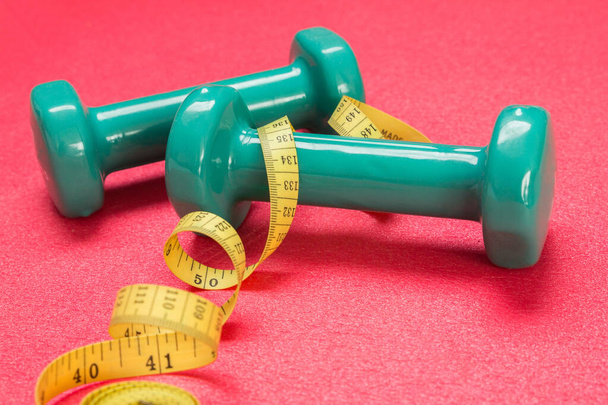 Stock photo of two dumbbells and a measuring tape on an exercise mat - Photo, Image