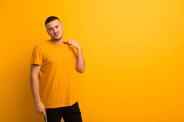 young handsome man feeling stressed, anxious, tired and frustrated, pulling shirt neck, looking frustrated with problem against flat background - Fotoğraf, Görsel