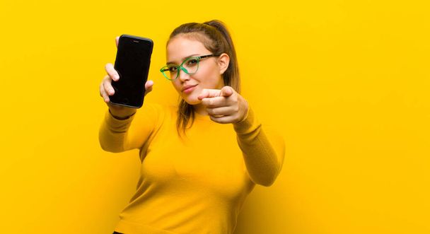 young pretty woman with a smart phone against yellow background - Fotó, kép