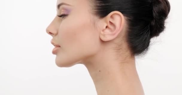 Closeup face of young woman with clean skin of face. Skin care. Beautiful girl with  sexy look turns to the camera. Beautiful healthy  woman with fresh skin of face over white background. Slow motion - Imágenes, Vídeo