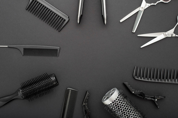 Flat lay composition with Hairdresser tools: scissors, combs, hair iron on black background with copy space for text in center. Frame. Hairdresser service. Beauty salon service. Hairdresser Set. - Photo, Image