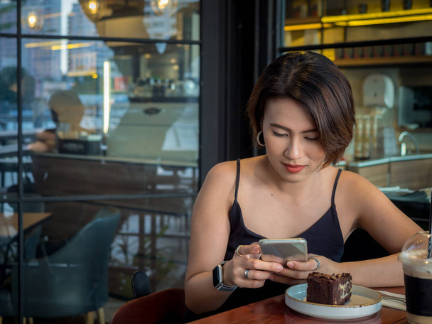 Gyönyörű ázsiai nő rövid haj segítségével smartphone és ivás c - Fotó, kép