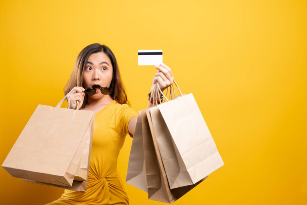 Happy woman holding shopping bags and credit card isolated over  - Fotoğraf, Görsel