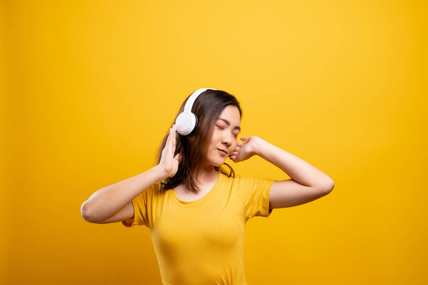 Frau mit Kopfhörer hört Musik auf isoliertem gelben Backgro - Foto, Bild