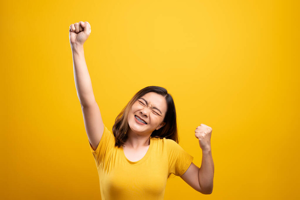 Mujer feliz hacer gesto ganador aislado sobre fondo amarillo - Foto, Imagen