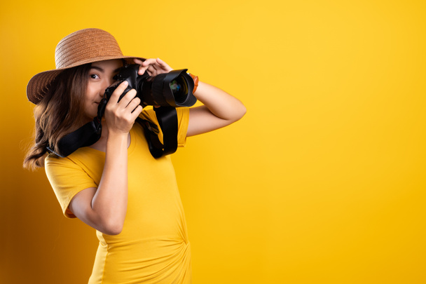 Woman in summer hat standing with photo camera isolated over yel - Foto, Imagen