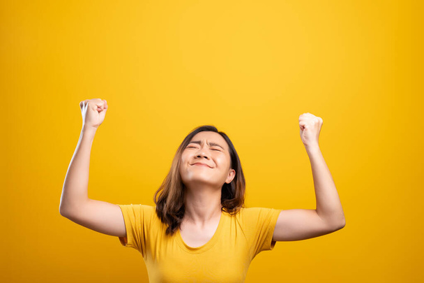 Ευτυχισμένη γυναίκα κάνει χειρονομία νίκης απομονώνονται πάνω από κίτρινο φόντο - Φωτογραφία, εικόνα