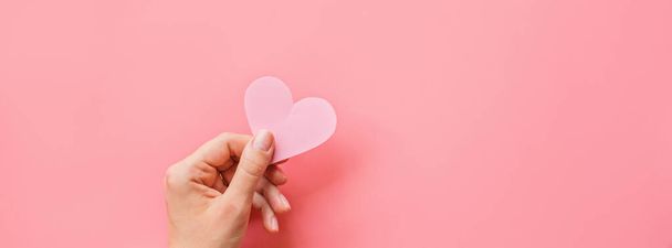 Valentine's day background. Female hands holding pink hearth. Flat lay, top view, mockup, template, copy space. Minimal abstract composition for 14 February celebration - Φωτογραφία, εικόνα