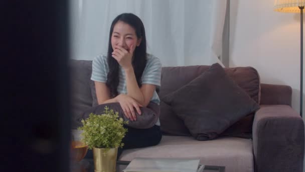 Aziatische vrouw van middelbare leeftijd genieten van vrije tijd ontspannen thuis. Lifestyle meisje gelukkig plezier kijken drama op TV en kijken entertainment in de woonkamer in moderne huis 's nachts concept. - Video