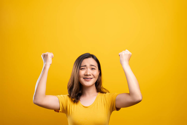 Щаслива жінка робить виграшний жест ізольованим на жовтому тлі
 - Фото, зображення