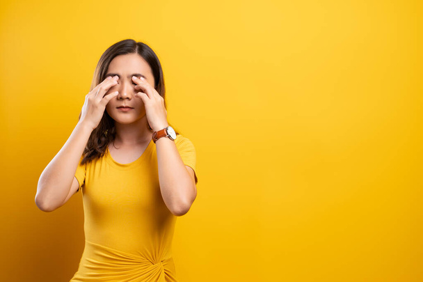 Woman has eyes pain isolated over yellow background - Foto, Imagem