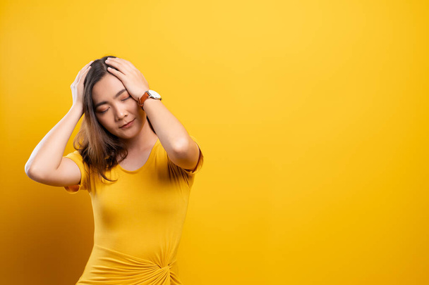 Woman has headache isolated over yellow background - Foto, imagen